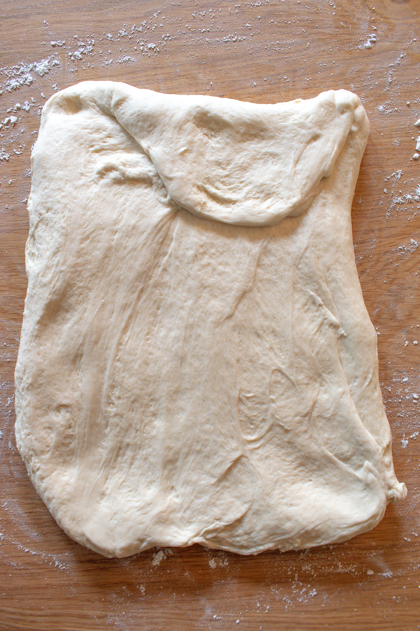 Overnight sourdough sandwich bread, flattened on a floured surface before rolling and shaping into a loaf.