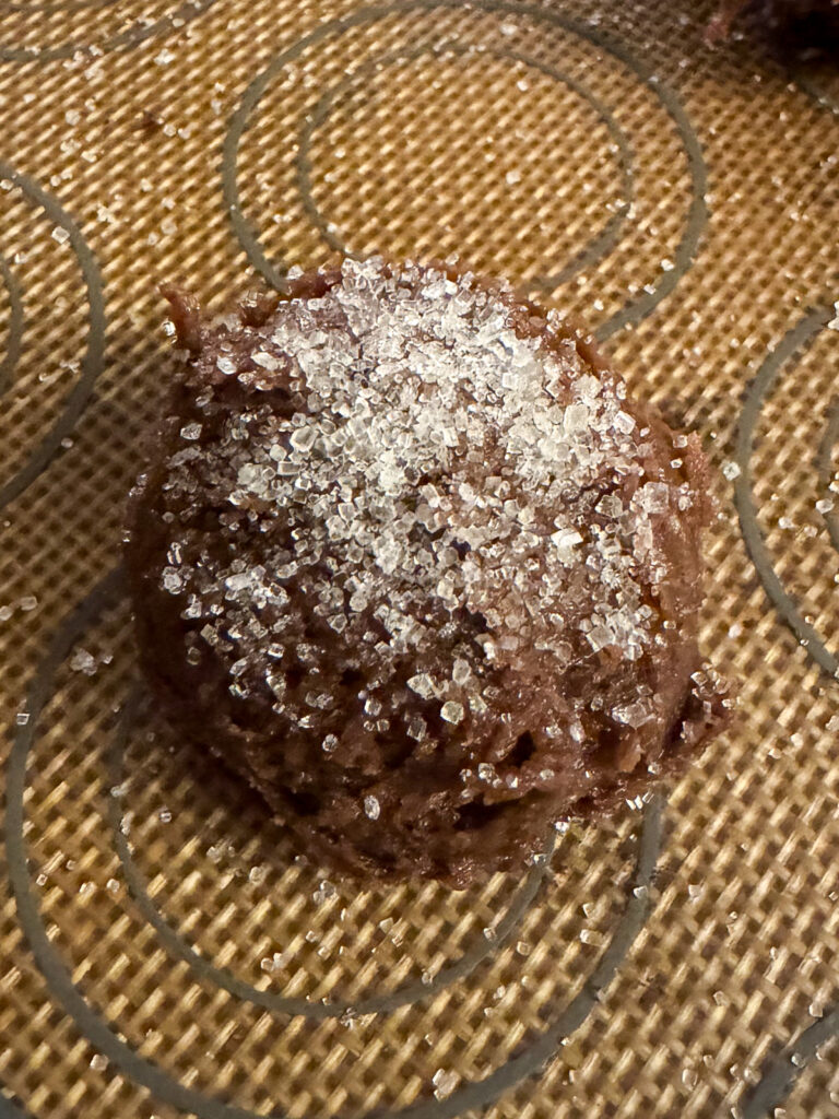 Sourdough discard chocolate peanut butter cookie dough ball rolled in sugar on a baking sheet.