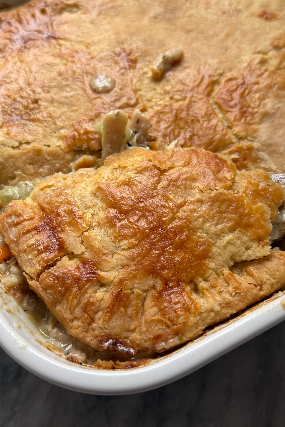 Golden sourdough discard rotisserie chicken pot pie with a serving spoon scooping some out.