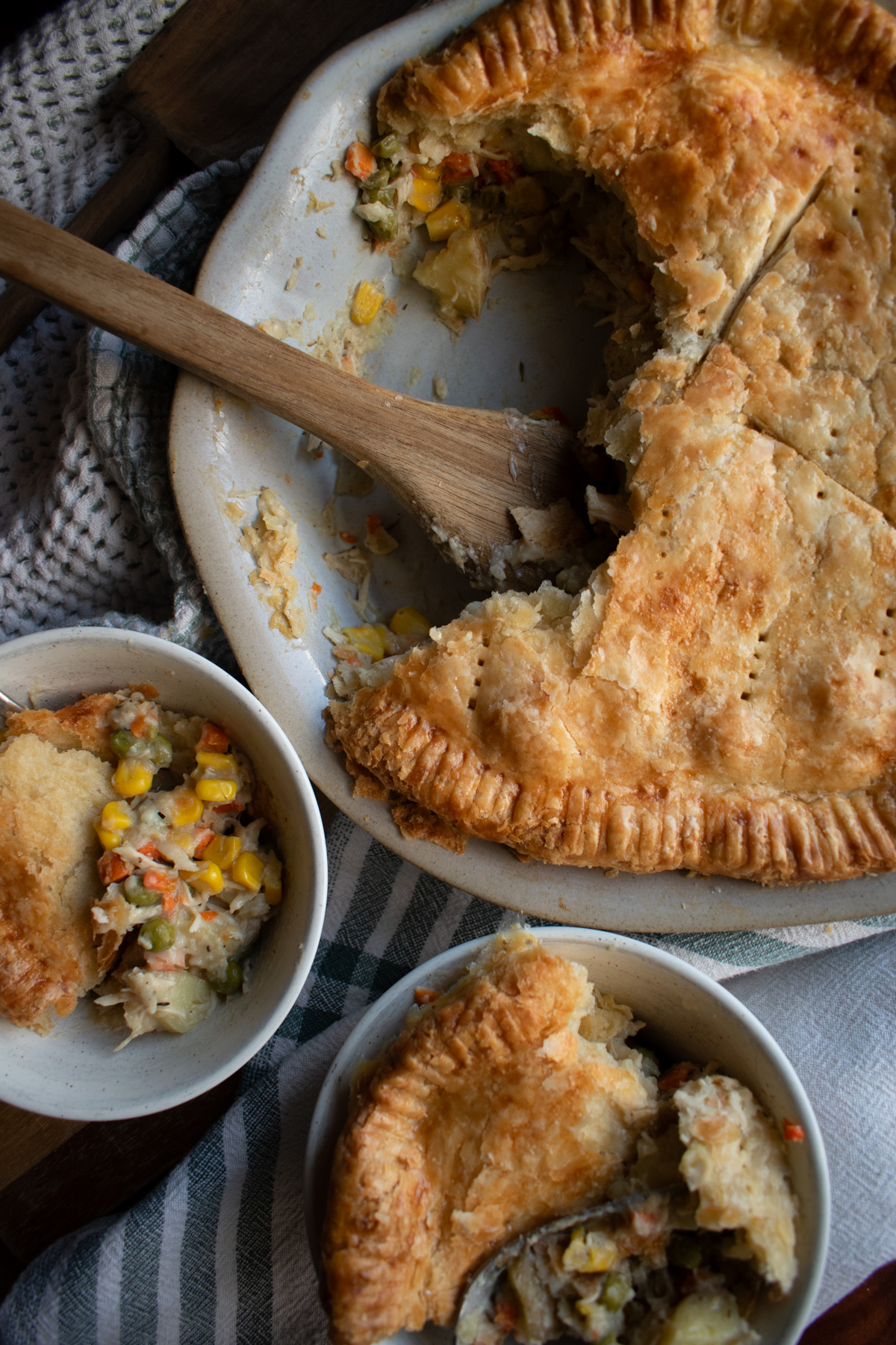 Sourdough discard rotisserie chicken pot pie in a pie dish and spooped into two small bowls with forks. 