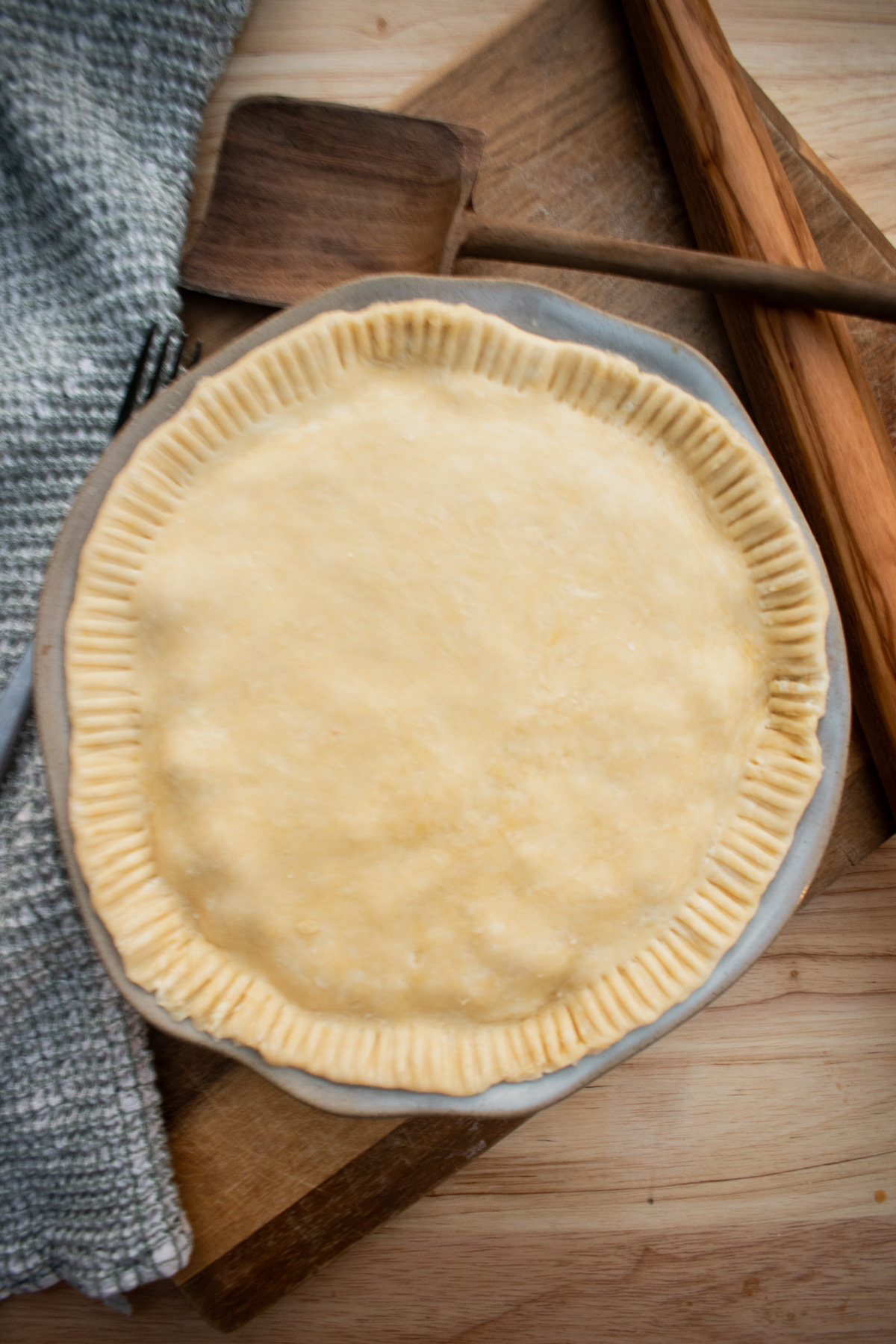 Sourdough pie crust draped over a pie dish before baking.