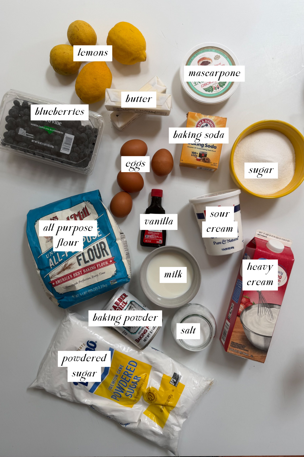 Picture of the ingredients needed for lemon blueberry mascarpone cake with ingredient labels. 