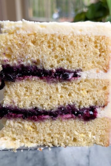 Picture of a slice of lemon blueberry mascarpone cake showing the three layers of cake and blueberry compote filling.