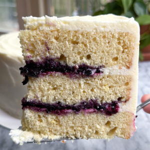 Picture of a slice of lemon blueberry mascarpone cake showing the three layers of cake and blueberry compote filling.