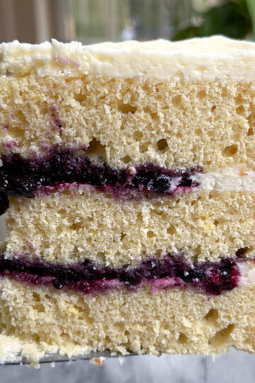 Picture of a slice of lemon blueberry mascarpone cake showing the three layers of cake and blueberry compote filling.