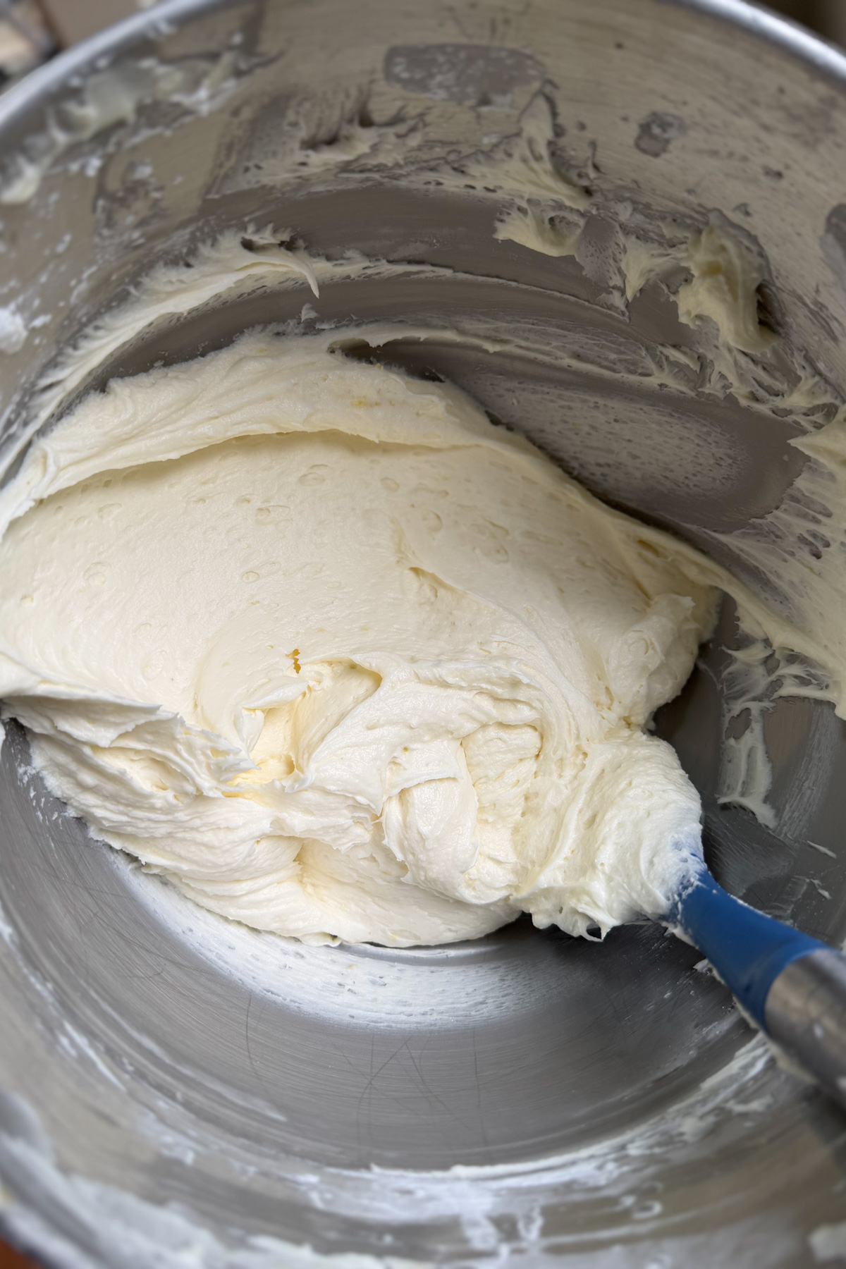 Lemon mascarpone buttercream in a stainless steel mixing bowl before being added to the lemon blueberry mascarpone cake.