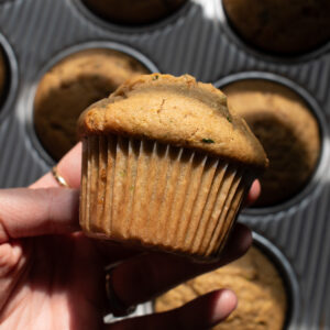 Hand holding a sourdough zucchini muffin.