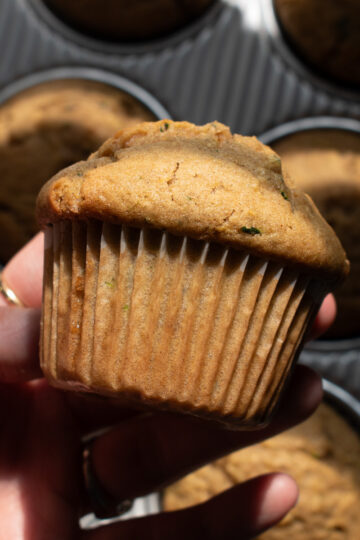 Hand holding a sourdough zucchini muffin.