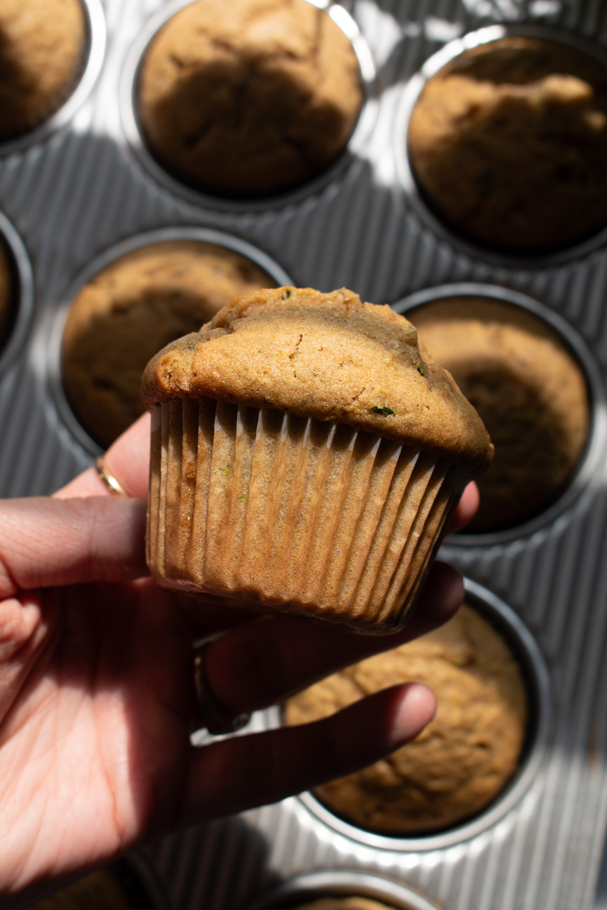 Hand holding a sourdough zucchini muffin.