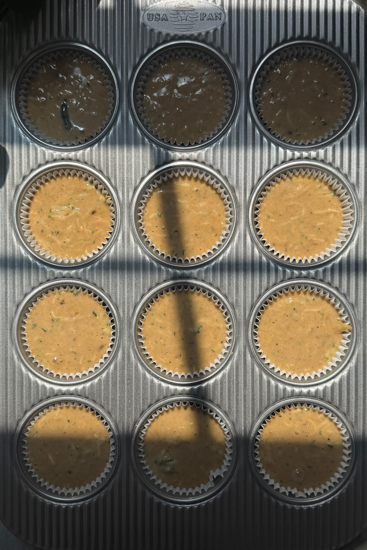 The batter for sourdough discard zucchini muffins in a 12-muffin pan before baking.