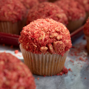 Strawberry crunch cupcake on a marble countertop surrounded by more cupcakes.