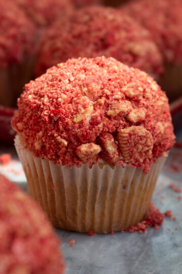 Strawberry crunch cupcake on a marble countertop surrounded by more cupcakes.