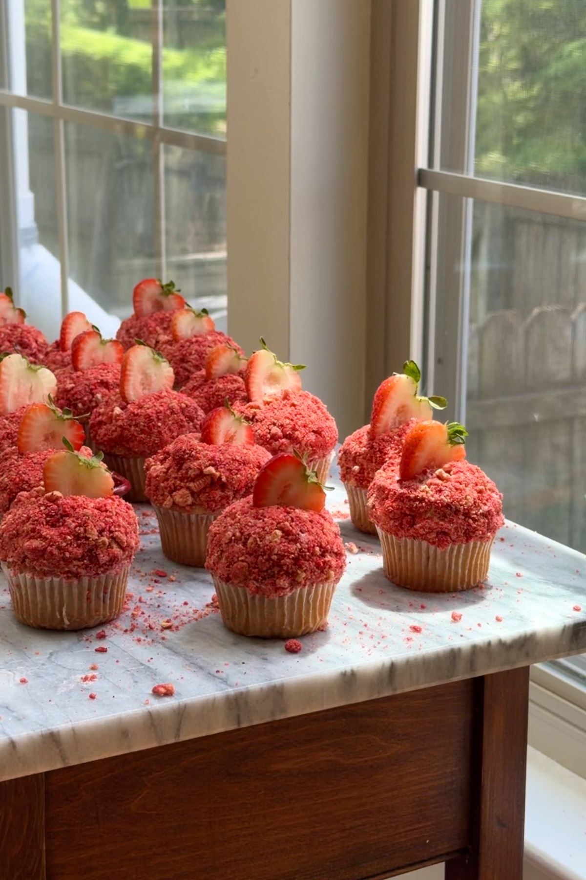 Strawberry crunch cupcakes on a marble countertop.