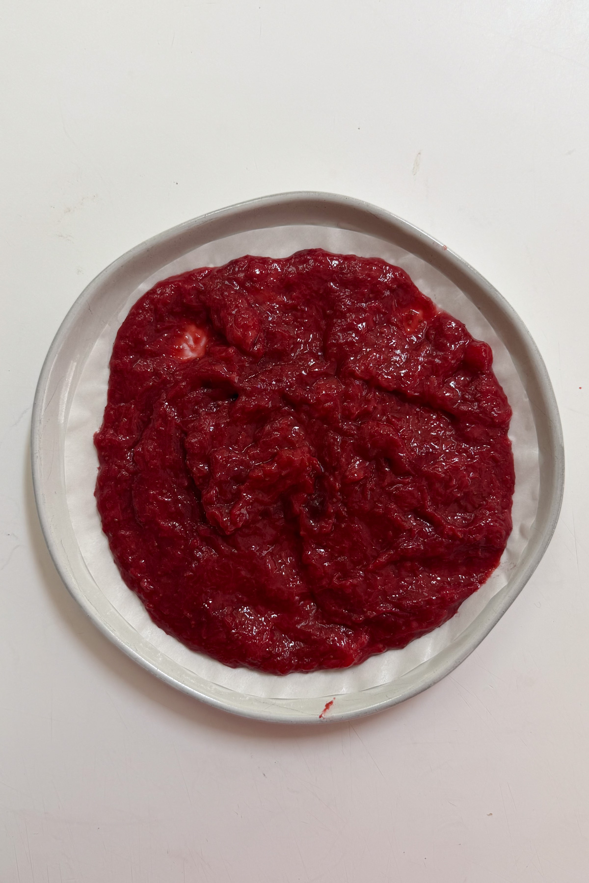 Strawberry reduction spread onto a plate to cool.