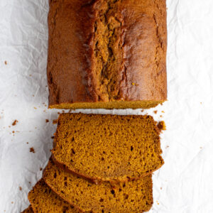Overhead picture of sourdough discard pumpkin bread cut into slices on crinkled parchment paper.