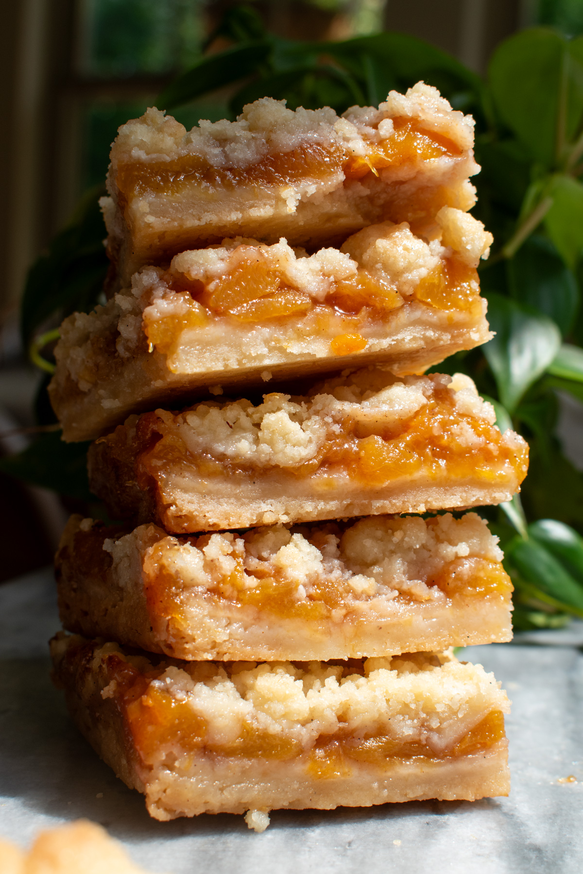 Five peach crumb bars stacked on top of each other to show the layers.