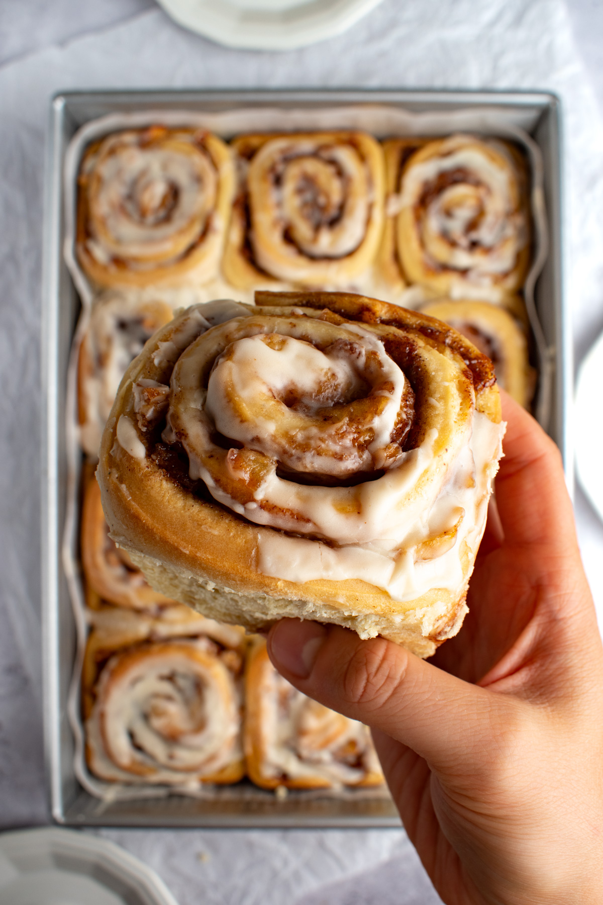 A hand holding apple pie cinnamon rolls.
