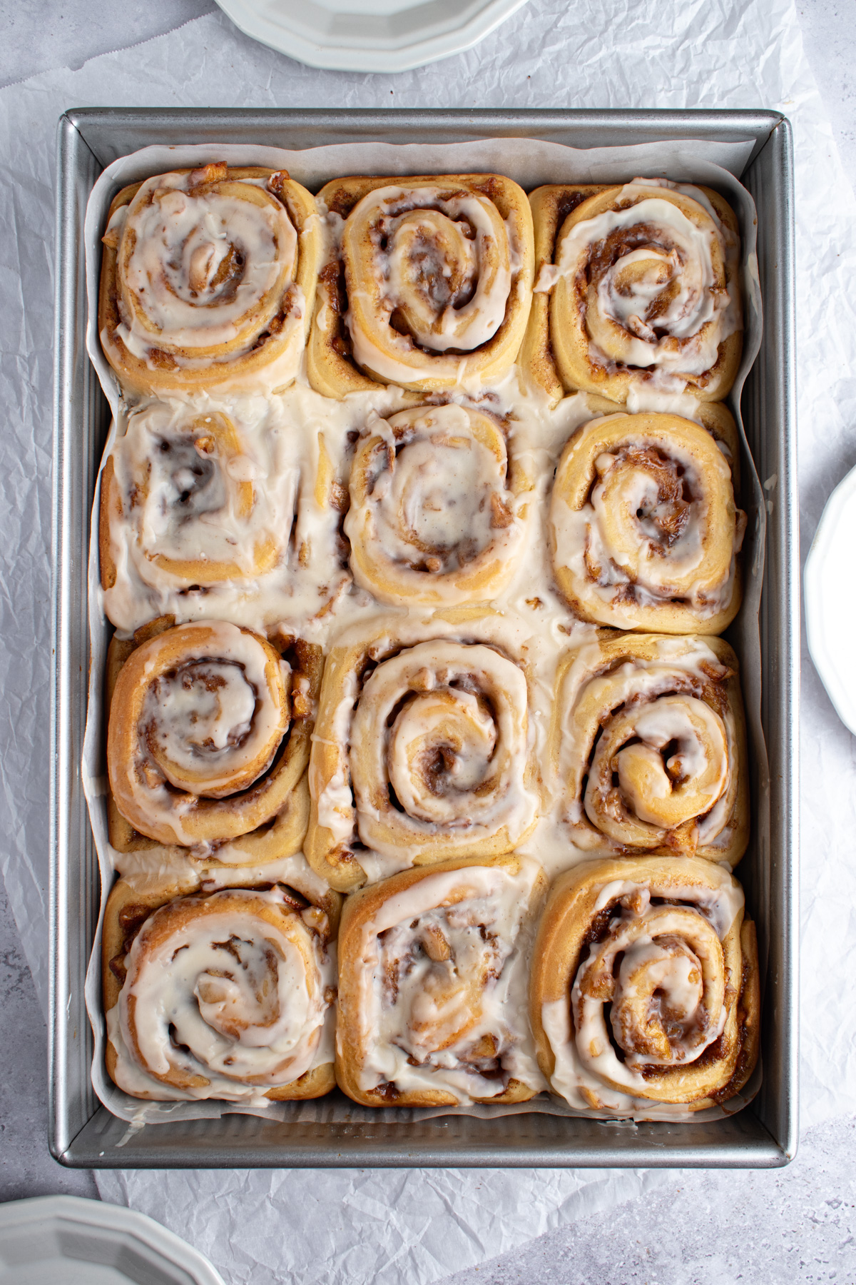 Overhead picture of apple pie cinnamon rolls with vanilla glaze in a 9x13 pan. 