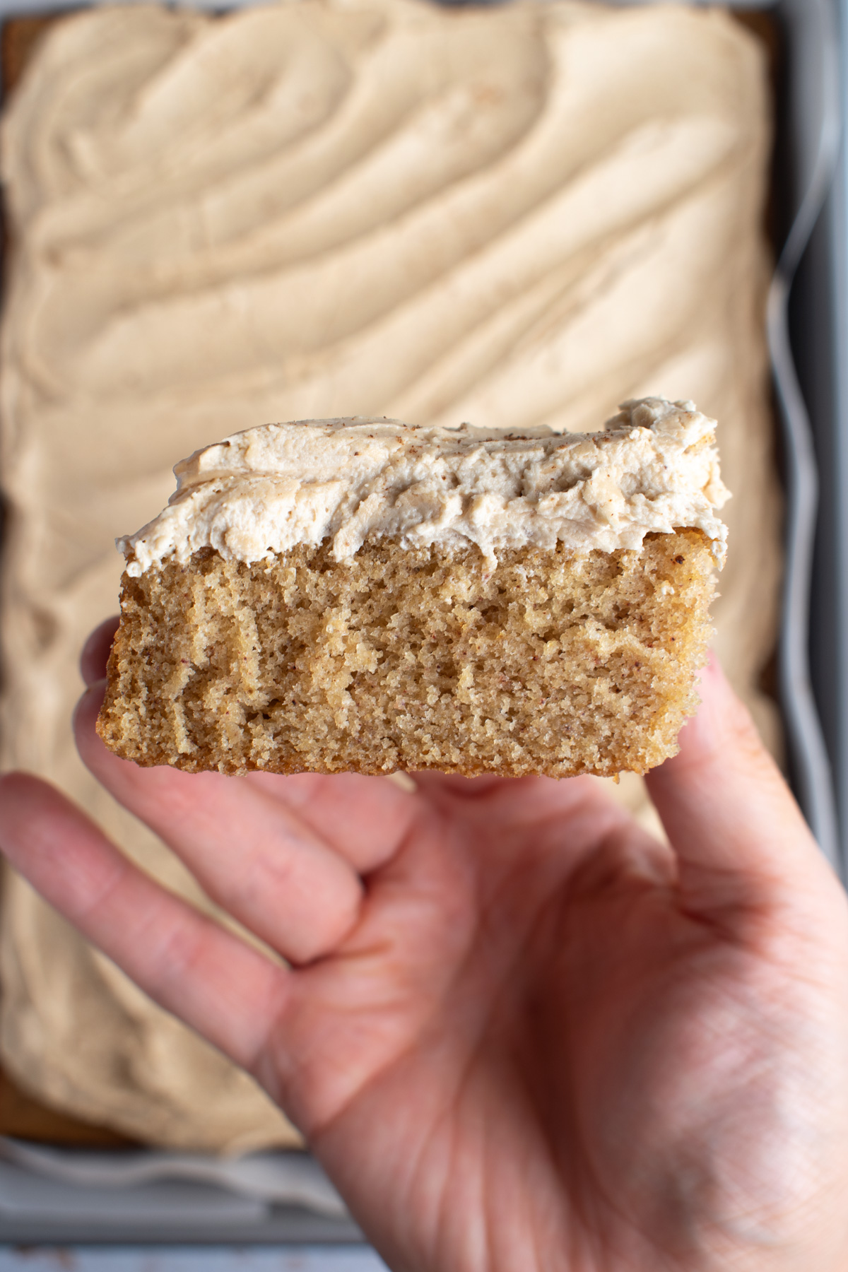 Overhead picture of a hand holding a slice of chai cake with espresso buttercream. 