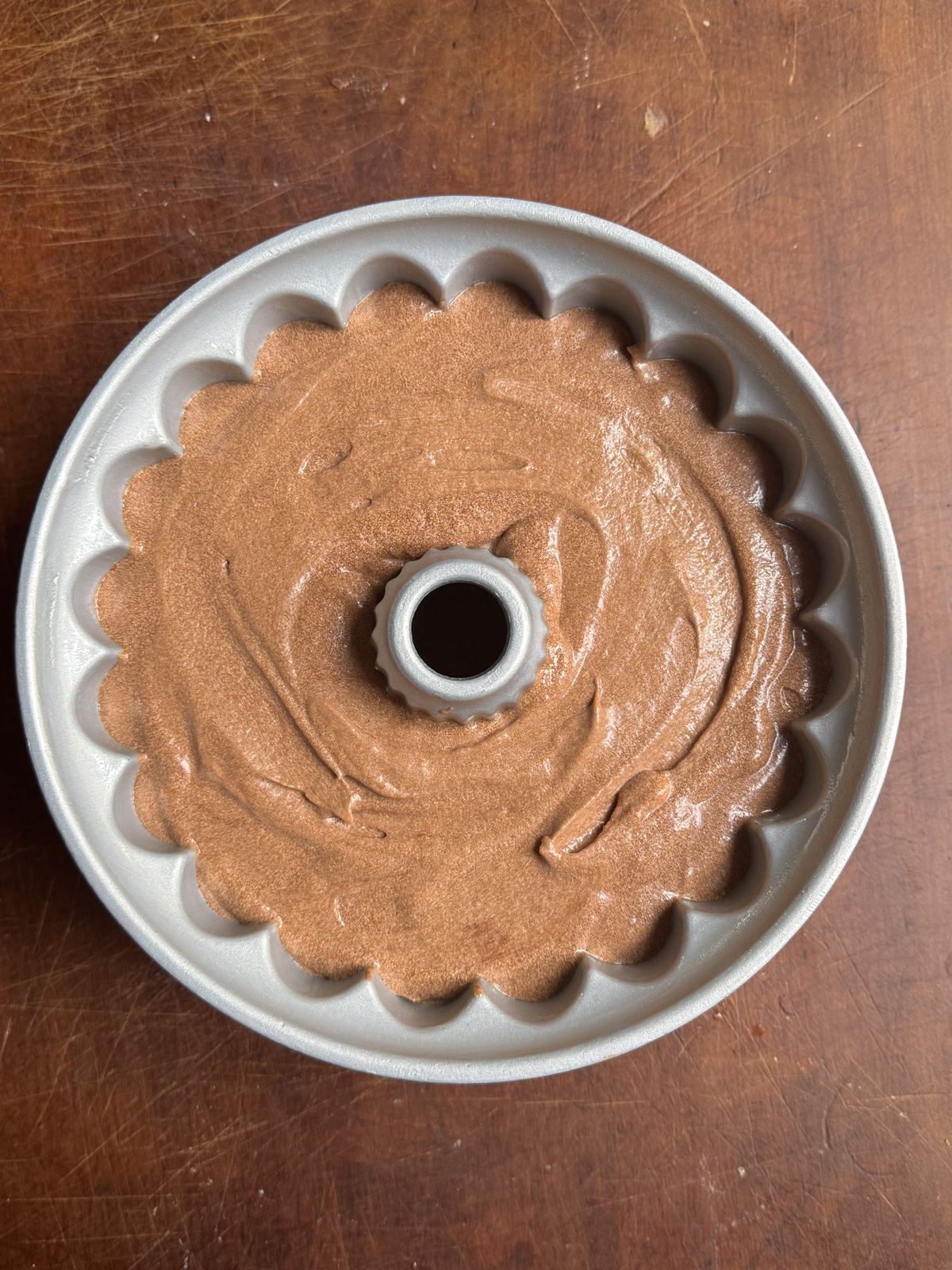Picture of chocolate sour cream pound cake batter in a metal bundt pan.