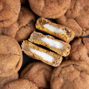 Overhead picture of sourdough discard pumpkin cheesecake cookies stacked on each other on a baking sheet.