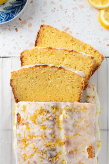 Overhead picutre of sourdough lemon pound cake on a cooling rack with three slices fanned out.