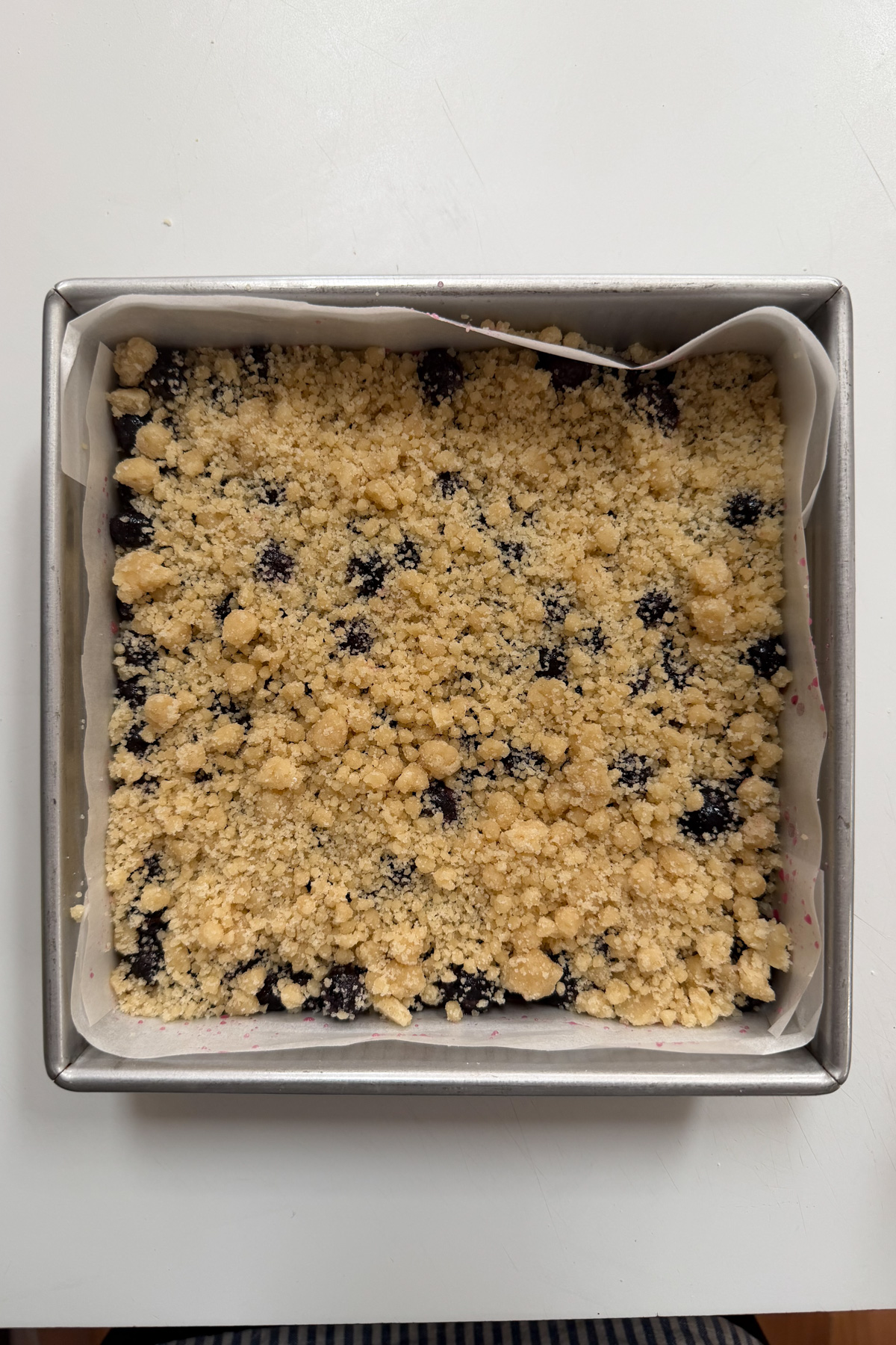 Picture of blueberry crumb bars in an 8x8 pan before being baked. 