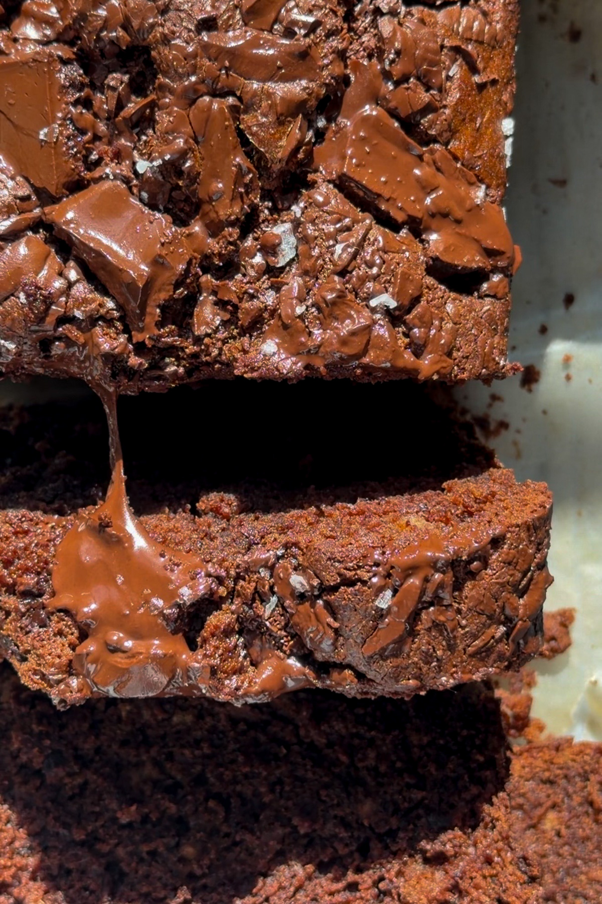 Overhead close-up image of sliced chocolate chunk banana bread with melted chocolate stretching between the slices.