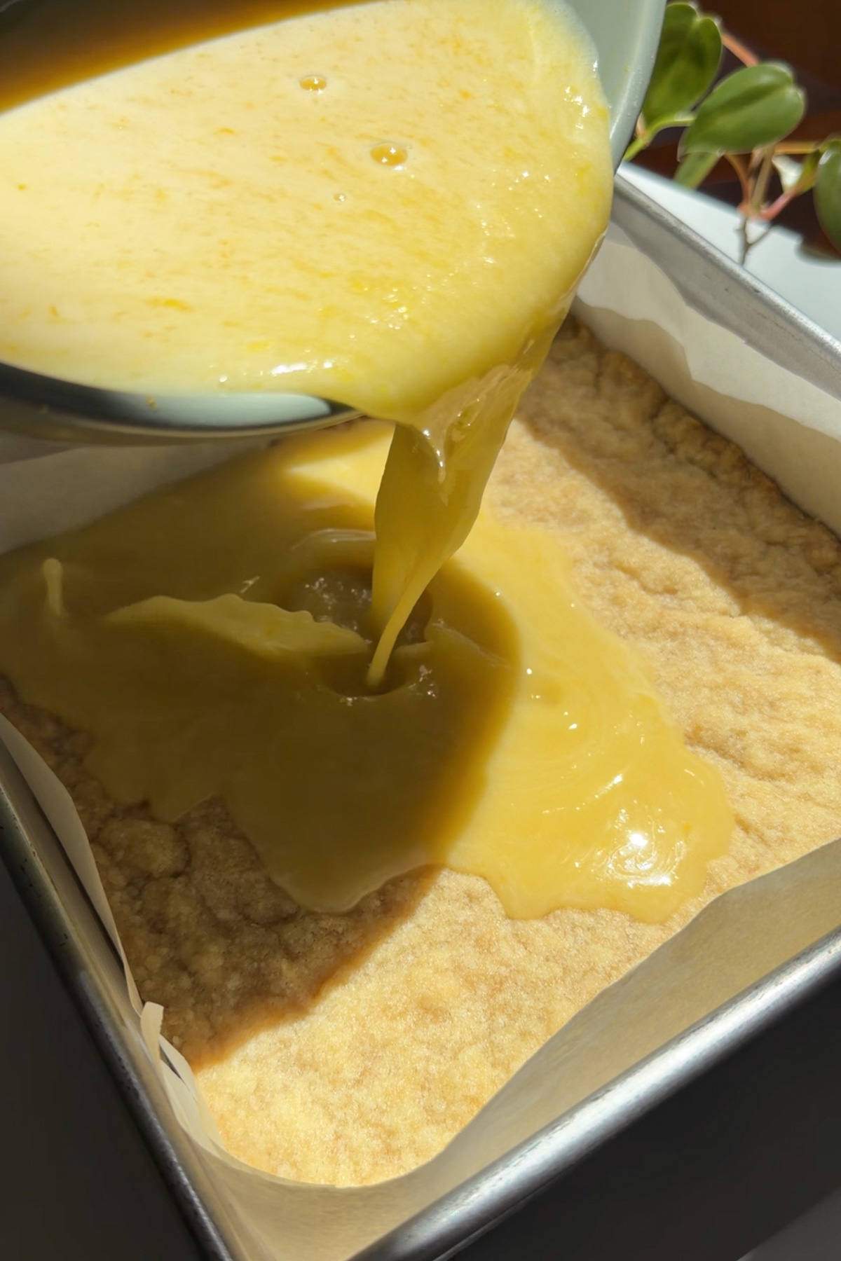 Picture of step 3 of the instructions for lemon crumb bars, showing the custard batter being poured onto the par-baked crust.