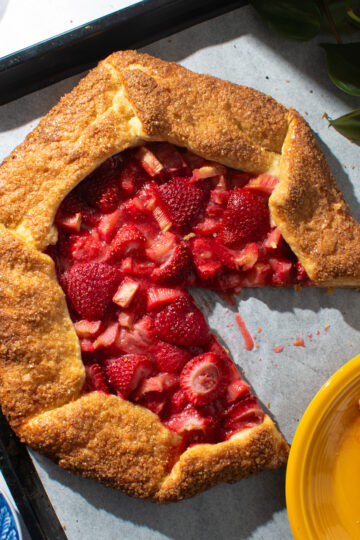 Overhead image of a strawberry rhubarb galette on a parchment paper-lined baking sheet.