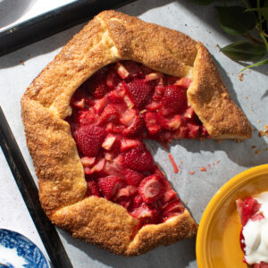 Overhead image of a strawberry rhubarb galette on a parchment paper-lined baking sheet.