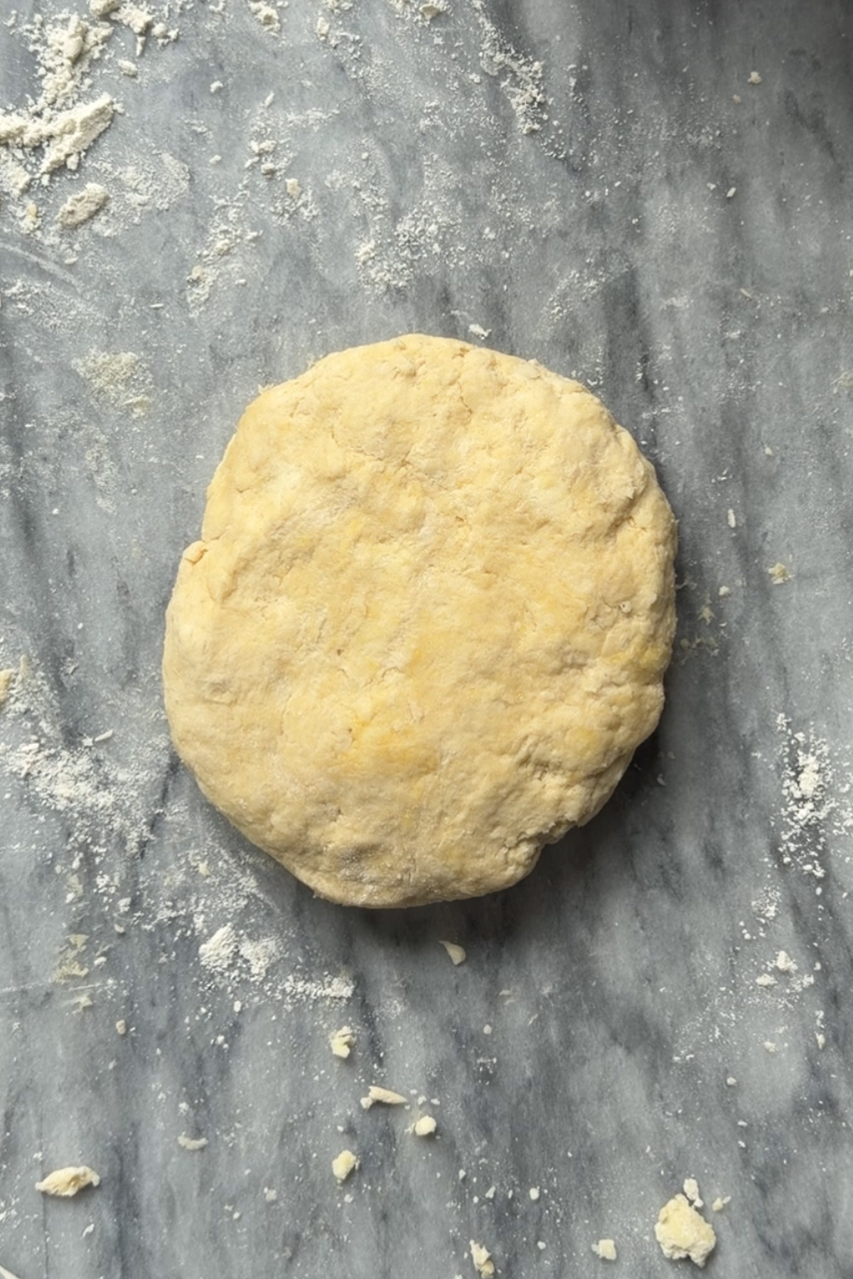 Overhead picture of the pie crust dough for rhubarb galette resting on a floured marble countertop.