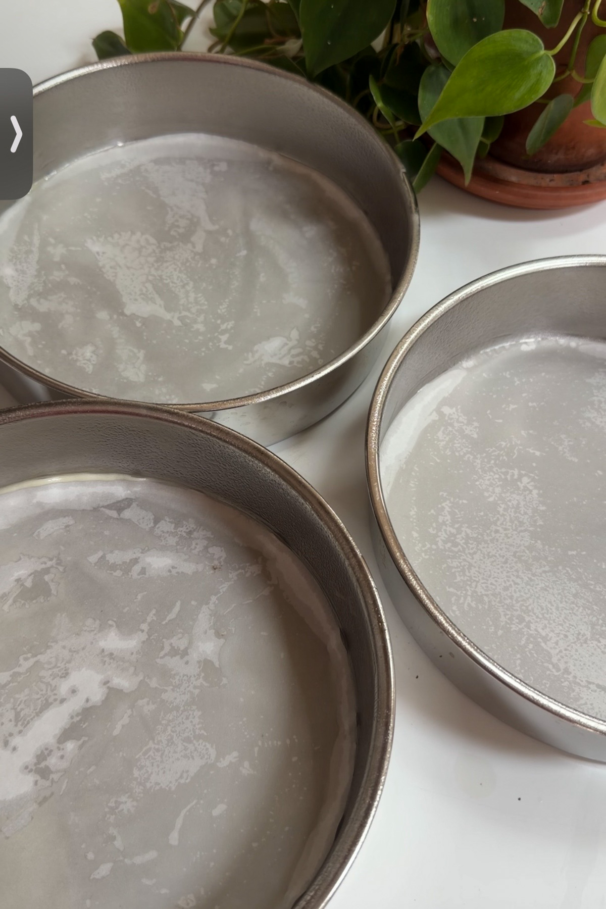 Three prepared 8-inch round cake pans that are greased and lined with parchment paper for sourdough discard funfetti cake