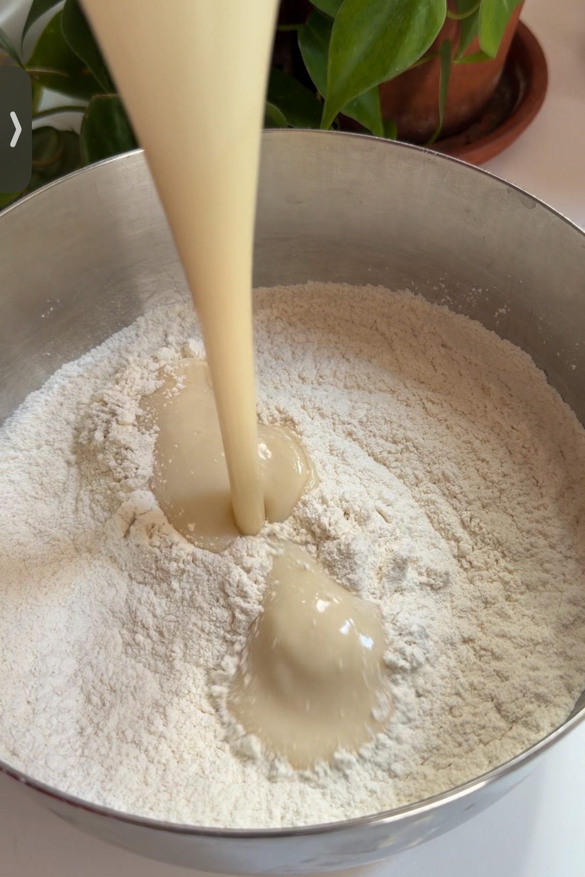 Wet and dry ingredients being combined in a stainless steel mixing bowl for sourdough discard funfetti cake before baking.