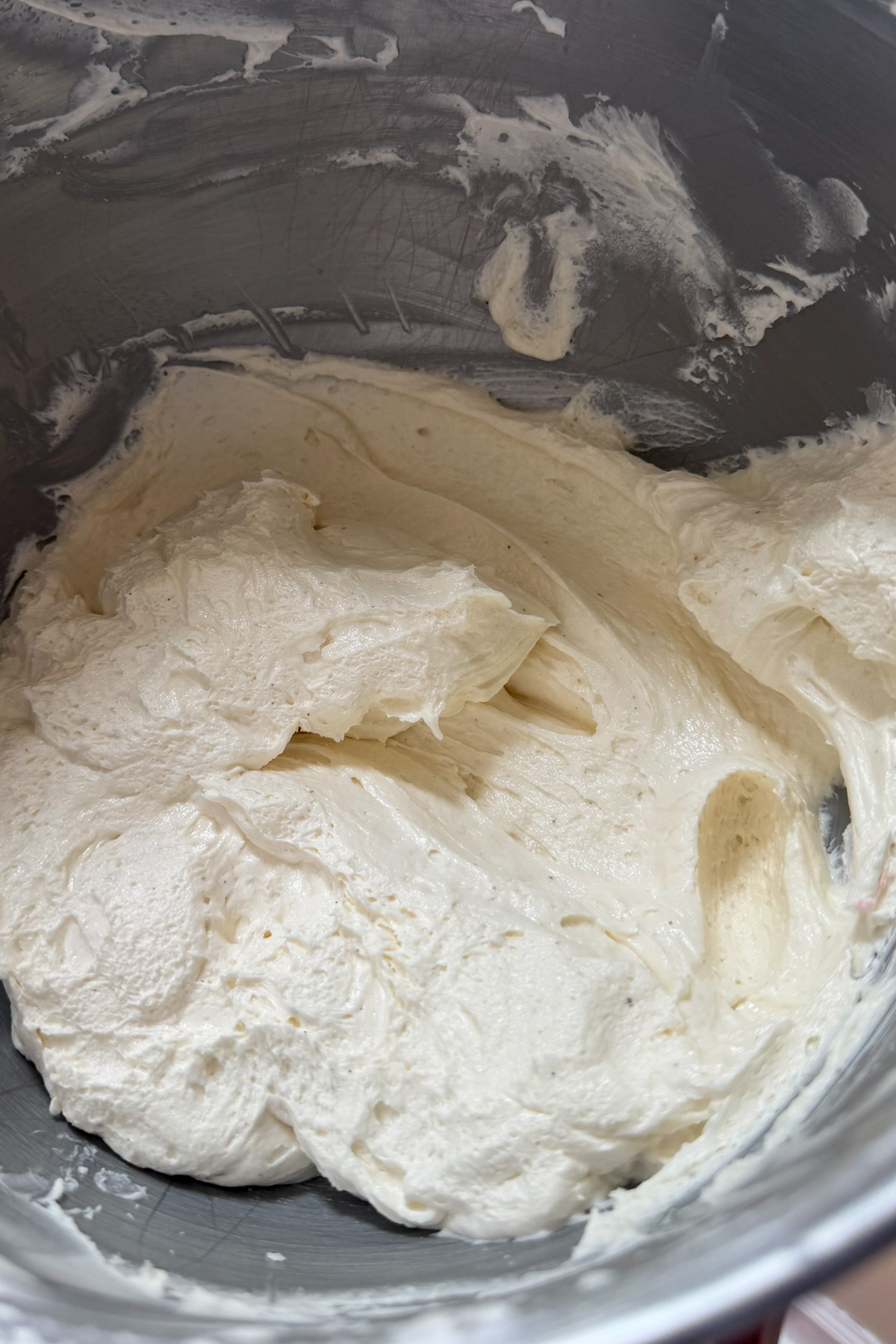 Vanilla buttercream frosting for sourdough discard funfetti cake in a stainless steel mixing bowl.