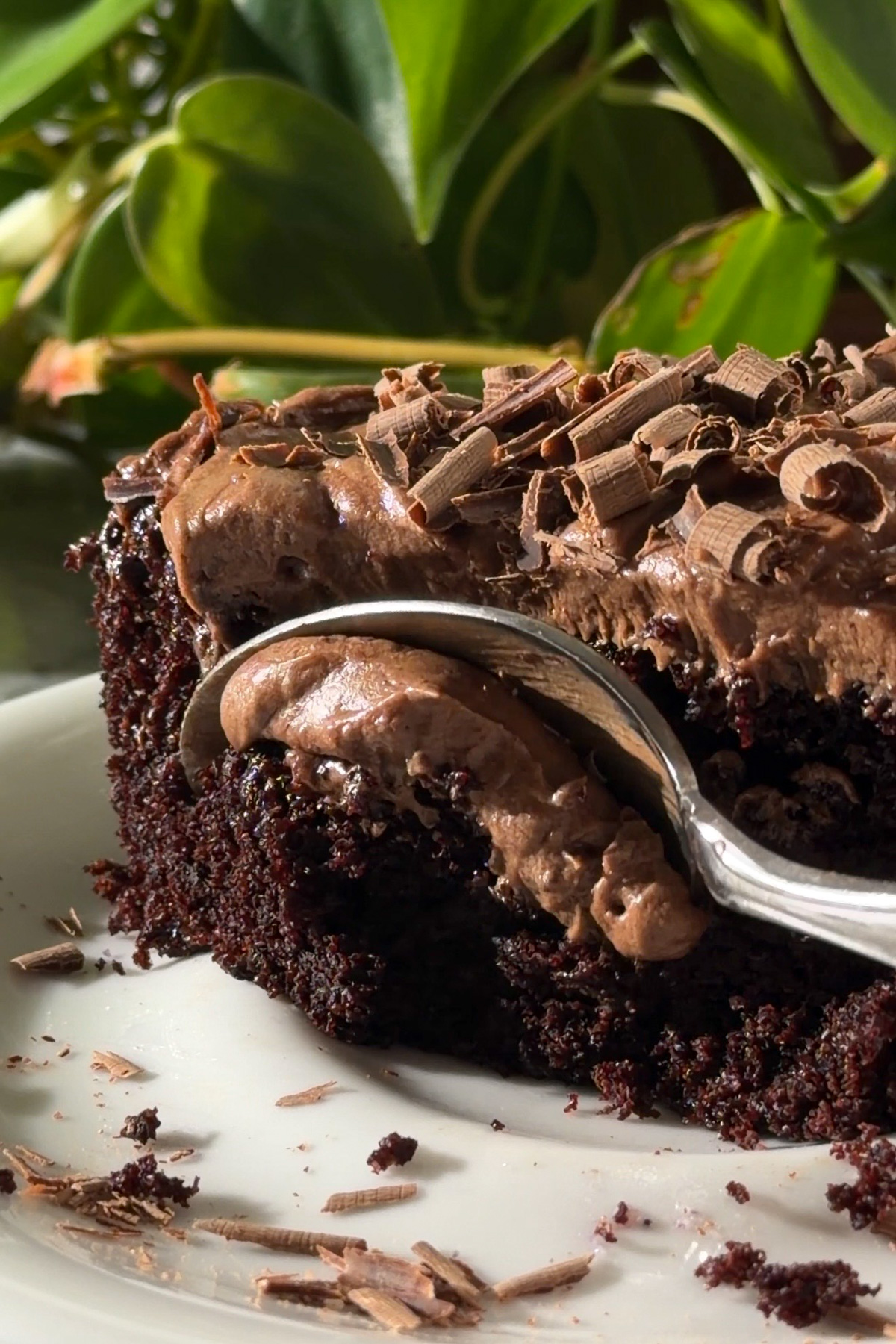 A spoon taking a bite out of a chocolate cream cheese sheet cake slice.
