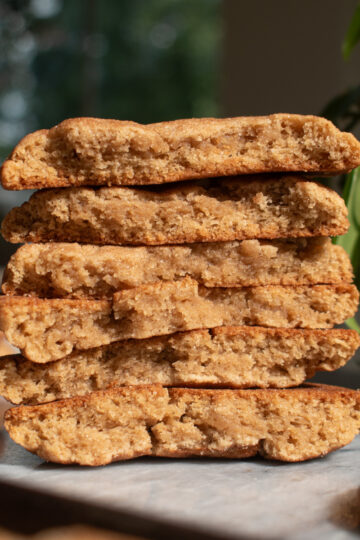 Three apple butter snickerdoodle cookies stacked on top of each other to show the chewy texture with a plant and window in the background.