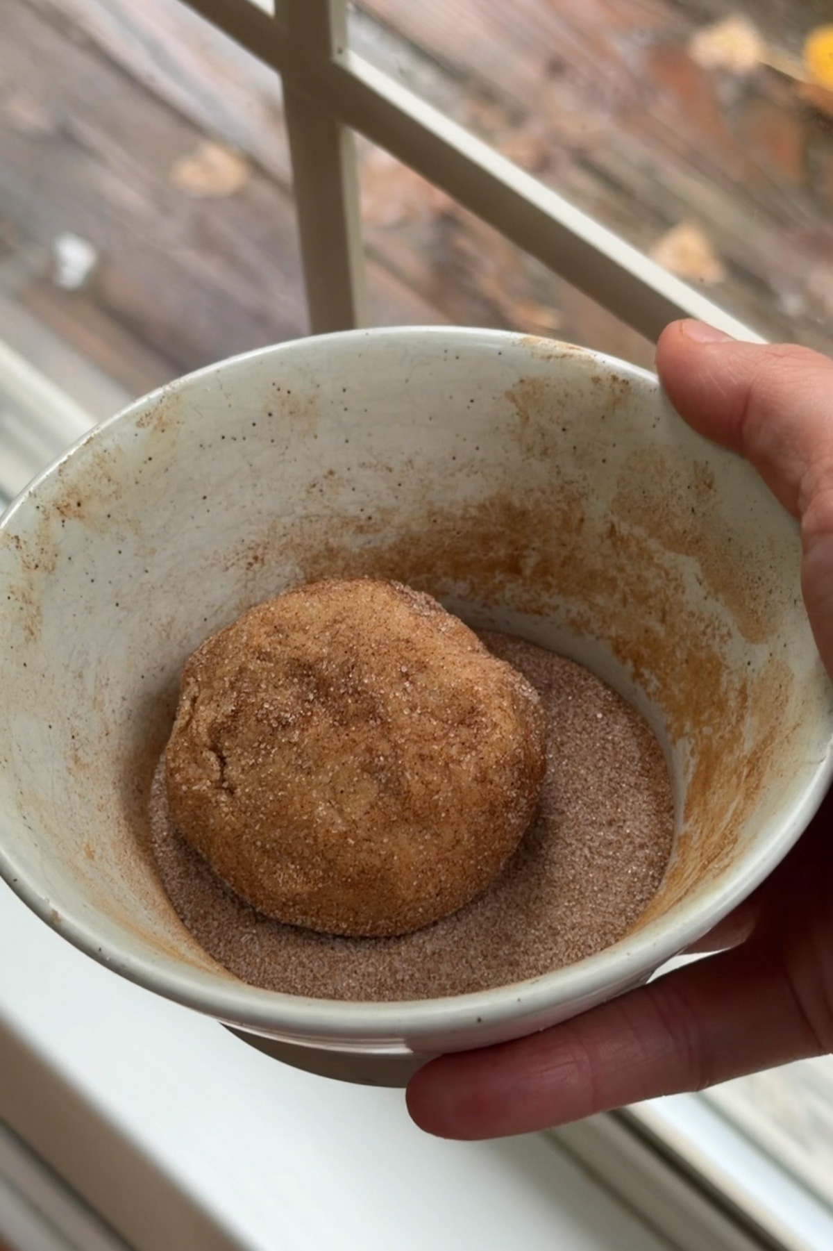 Apple butter snickerdoodle cookie dough balls in a bowl of cinnamon sugar before baking.