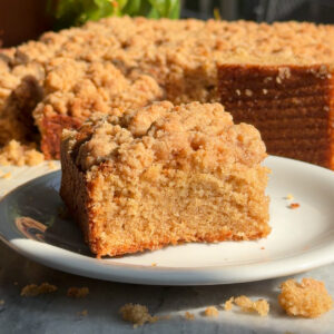 A slice of applesauce crumb cake on a white plate.
