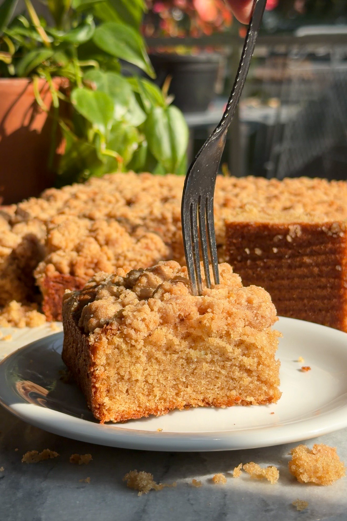 A fork cutting into a slice of New York-style applesauce crumb cake.
