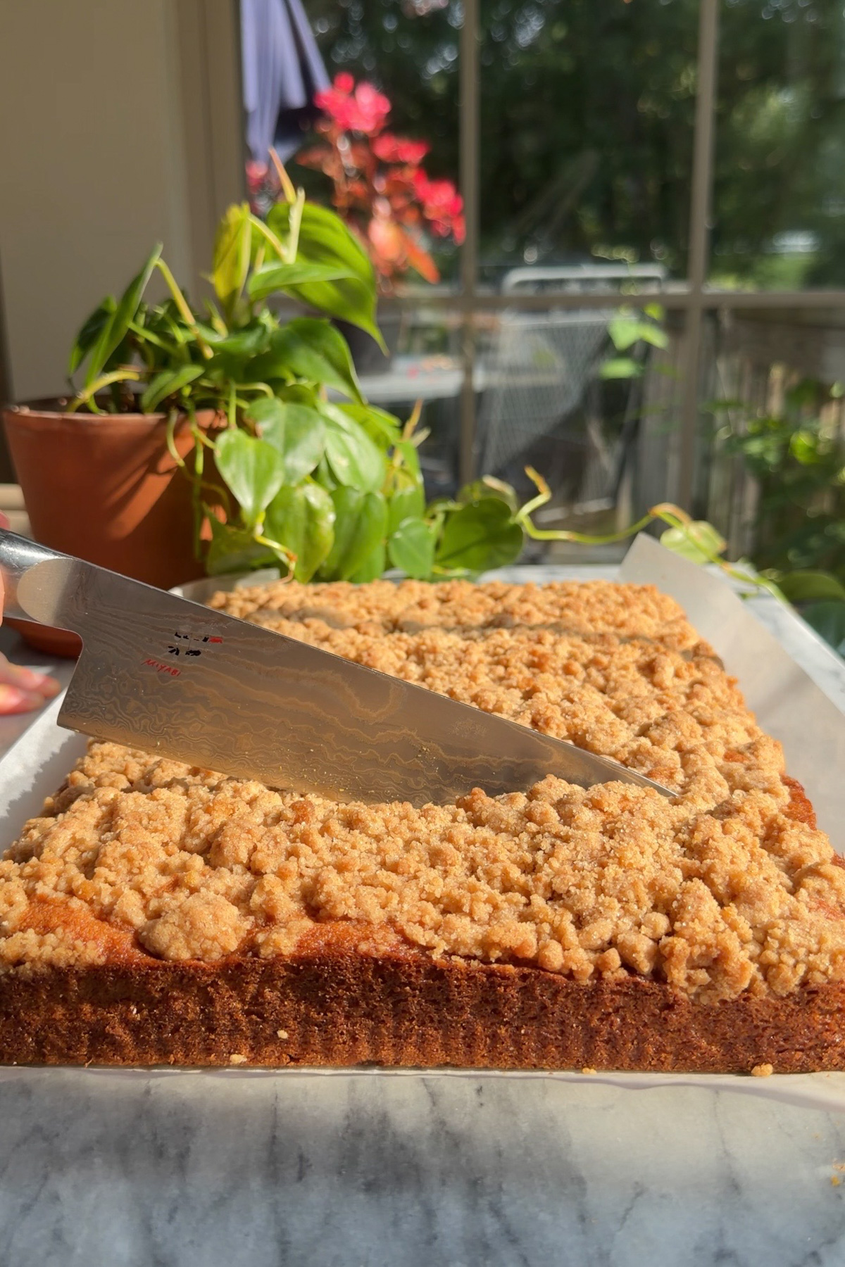 A knife cutting into a finished New York-Style Applesauce Crumb Cake.