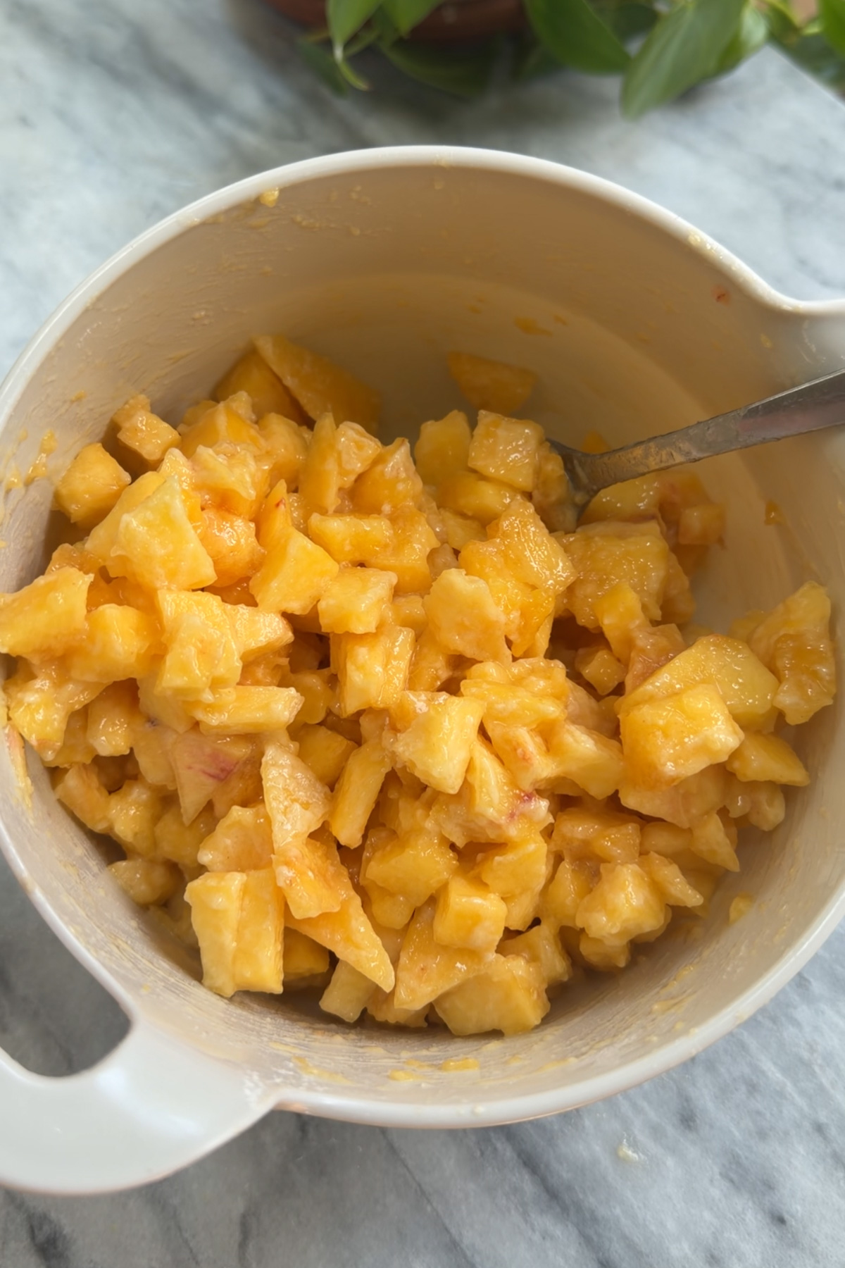 Chopped peaches tossed in flour and sugar in a mixing bowl before being added to brown butter peach coffee cake. 