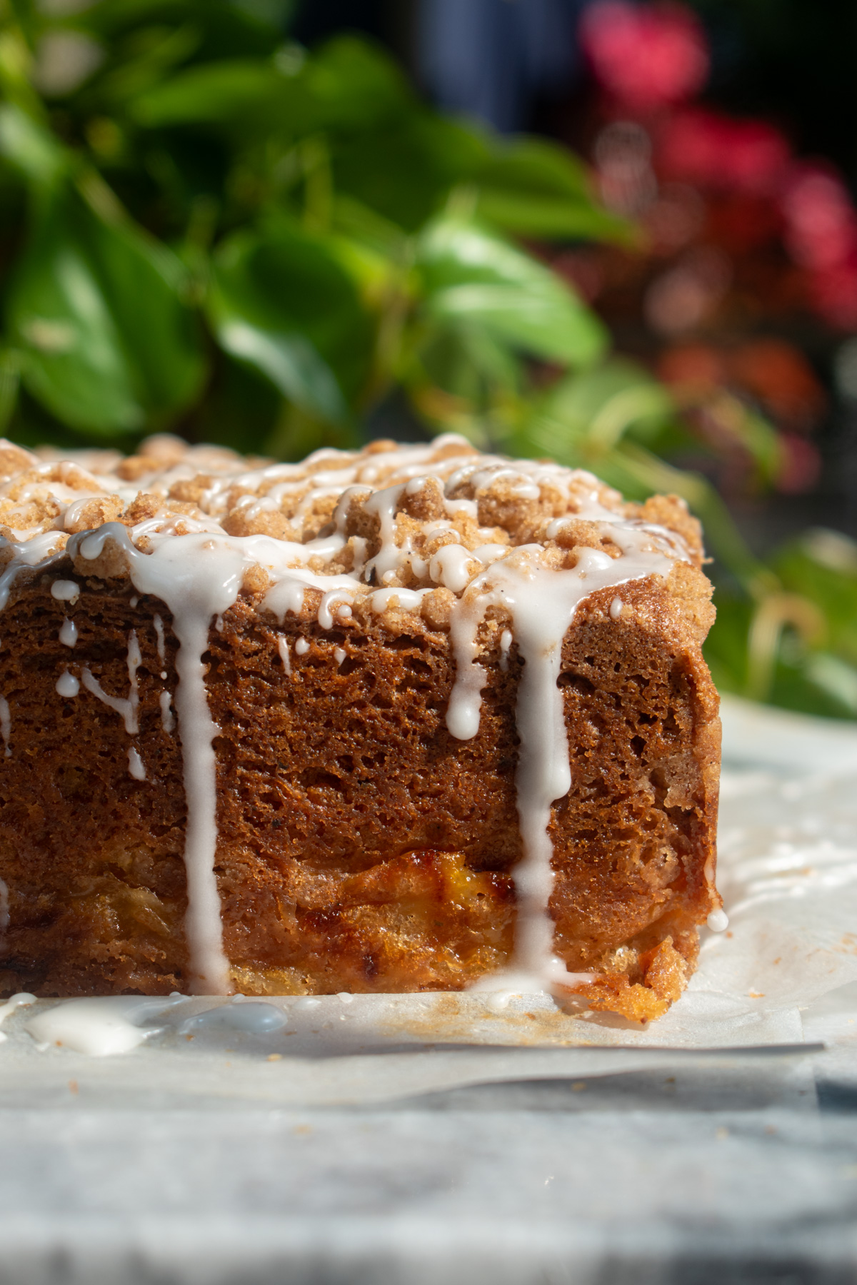 Finished brown butter peach coffee cake with vanilla glaze drizzling down the sides.