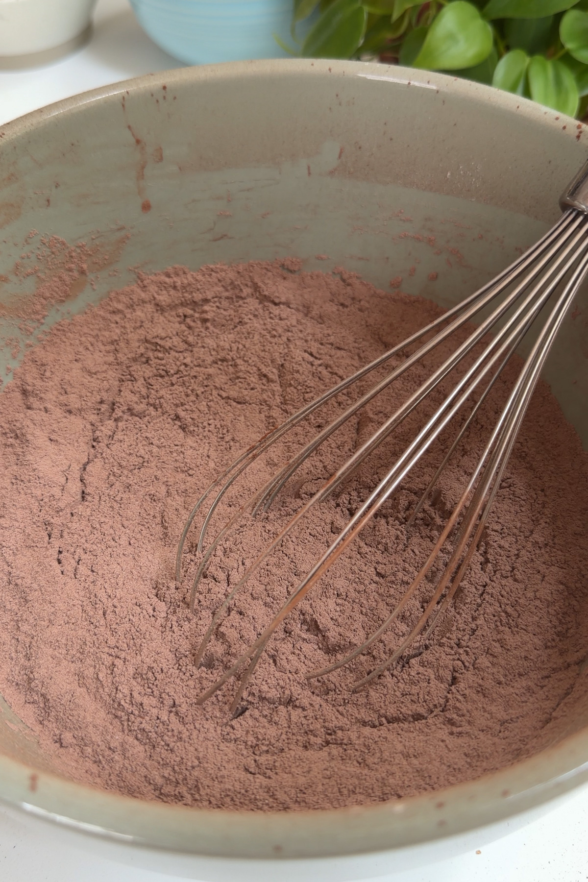 Dry ingredients in a green mixing bowl for a dark chocolate raspberry layer cake.