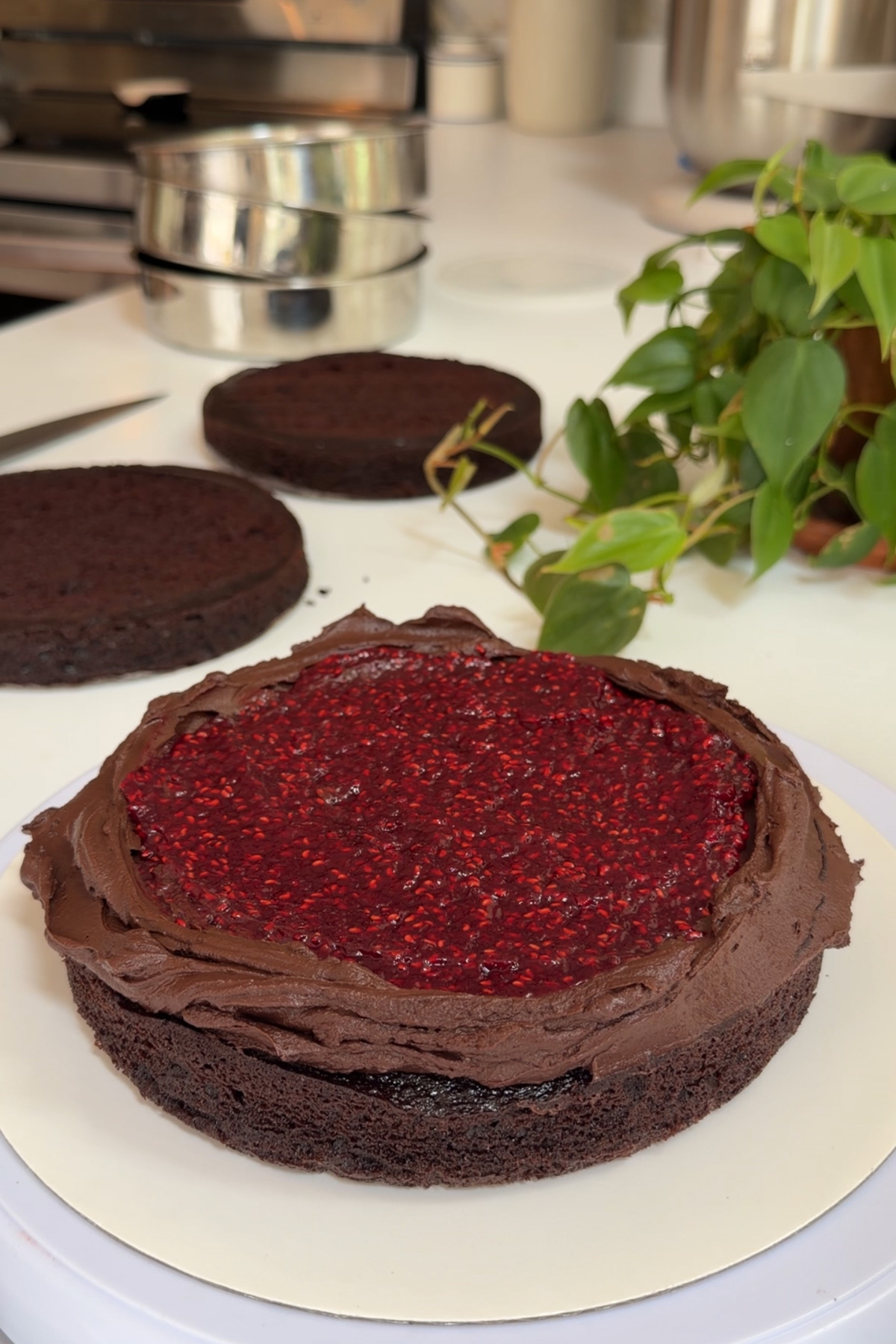 The first layer of a dark chocolate raspberry layer cake with chocolate ganache frosting smoother over the top with raspberry ganache in the center.