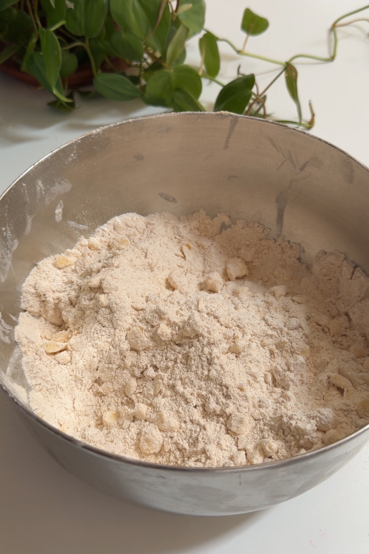 Butter cut into flour in a stainless steel mixing bowl for maple pecan scones.
