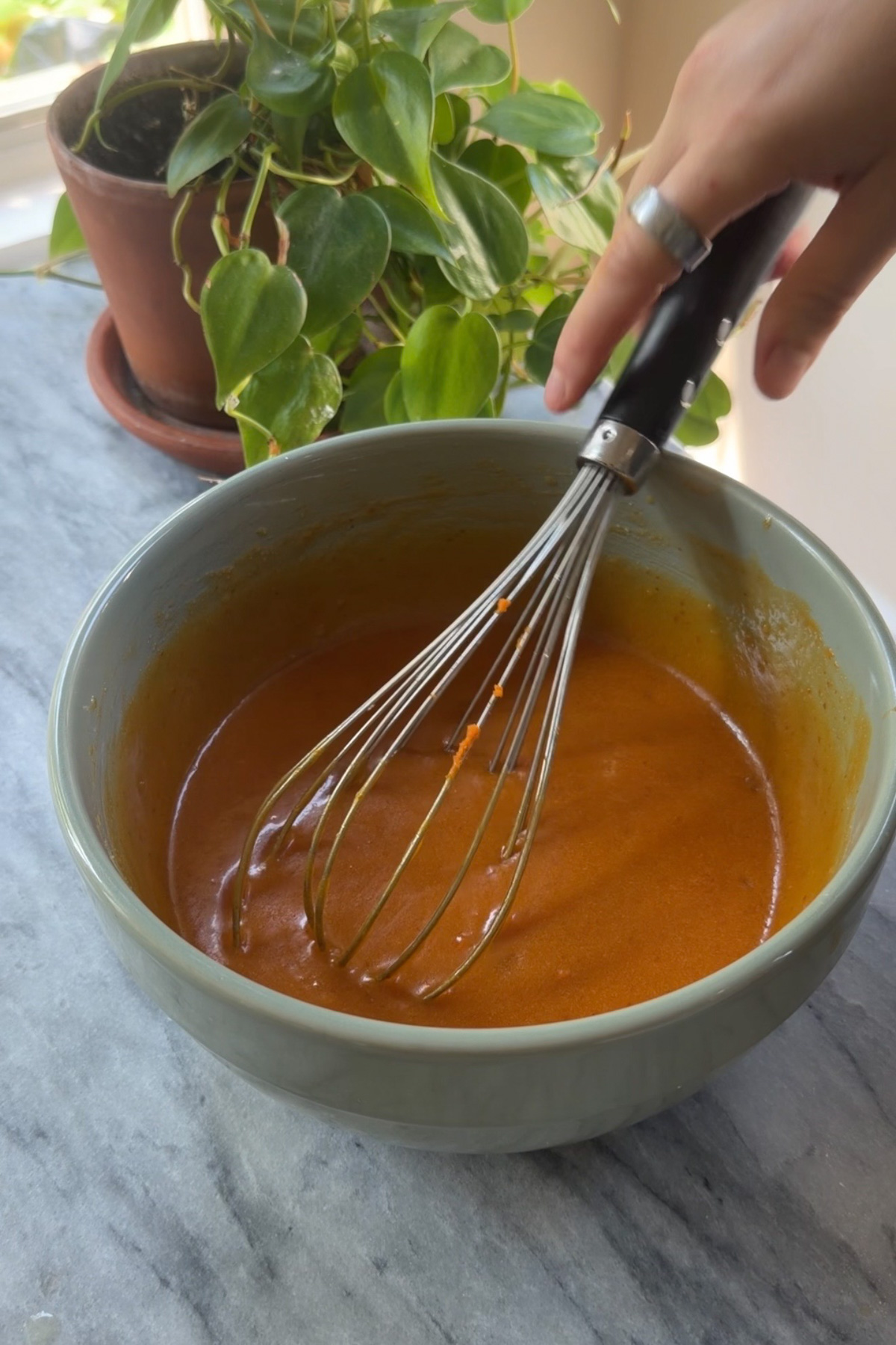 The wet ingredients for cinnamon sugar pumpkin blondies in a mixing bowl with a large whisk resting in it.