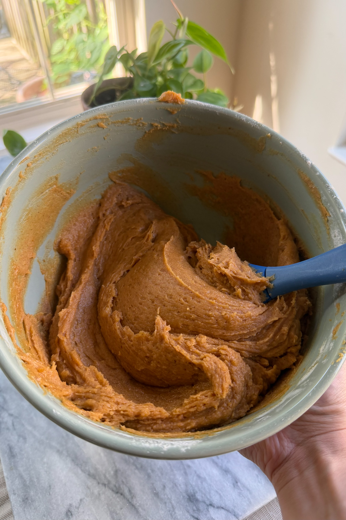 The batter for cinnamon sugar pumpkin blondies in a mixing bowl with a blue silicone spatula resting in it.