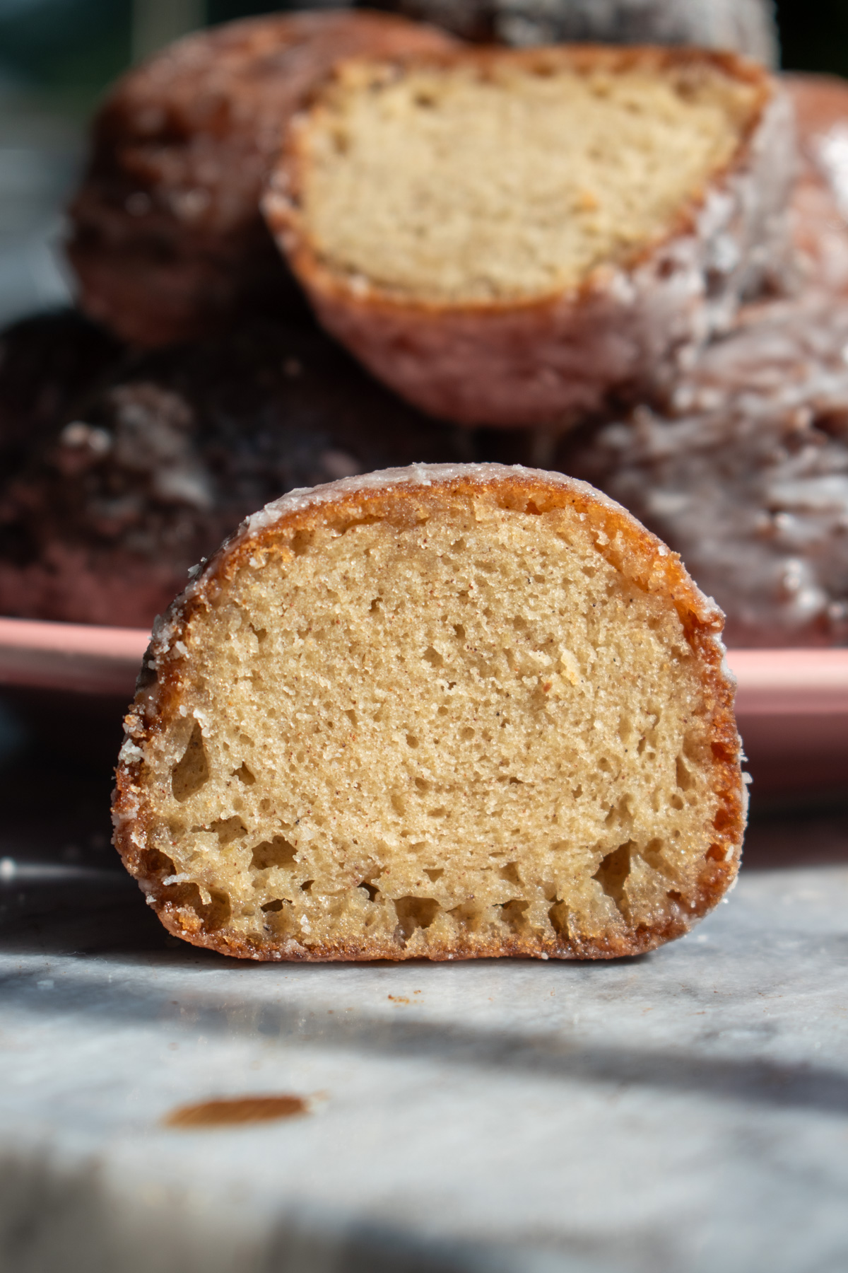  A glazed applesauce fritter that is cut in half to show its tender crumb and crackly crust.