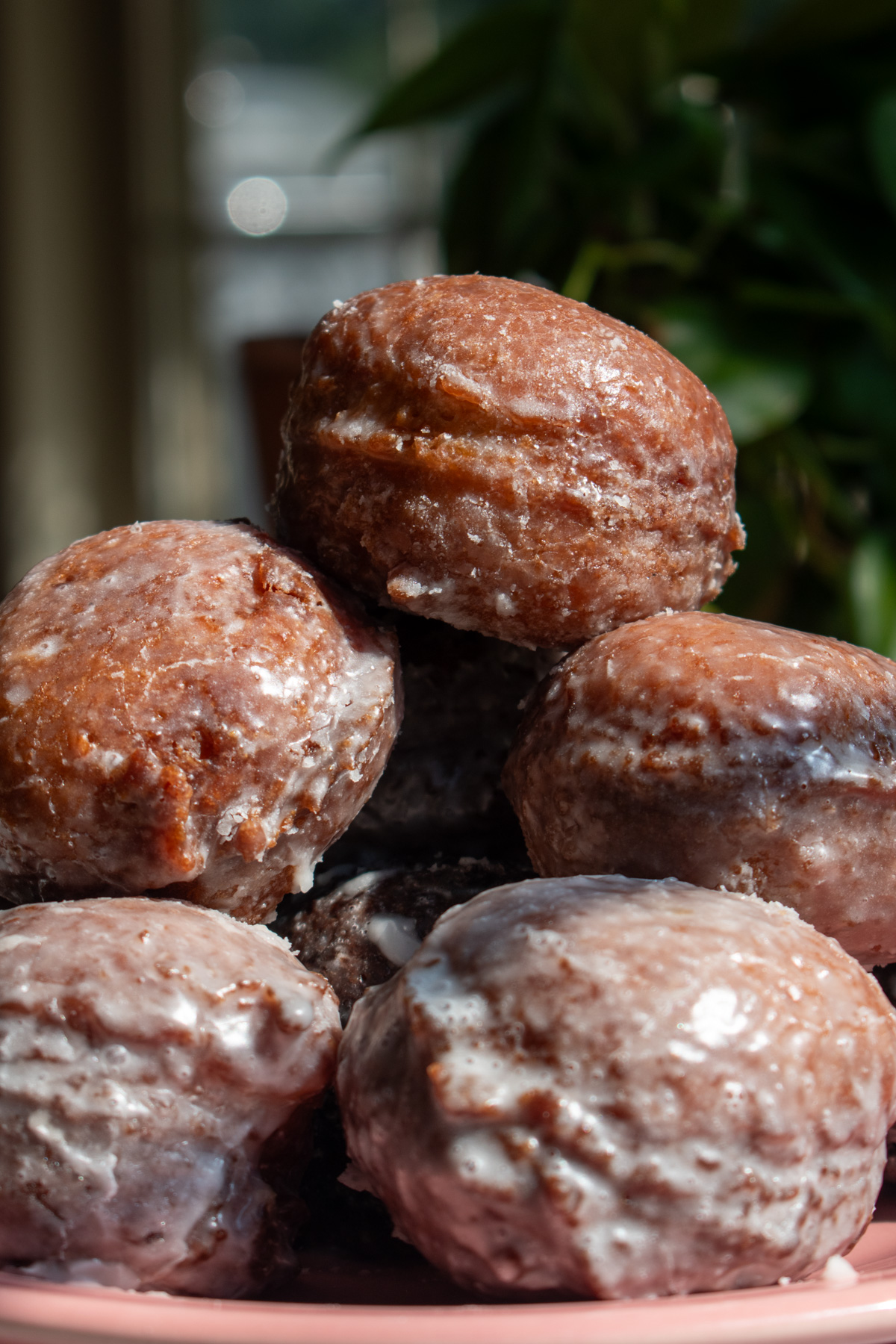 Glazed applesauce fritters stacked on top of each other to show their shiny, cracked texture.